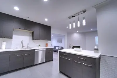 a kitchen with black cabinets and white counter tops at Modern LA Home - King Bed, Outdoor Living, Firepit in Los Angeles