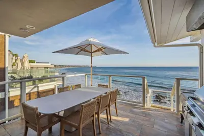a table with an umbrella on a balcony with the ocean at The Getaway Oceanfront Villa in Malibu by Stay Awhile in Malibu