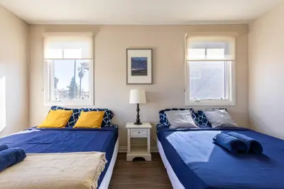 two beds in a room with two windows at Getaway 4BR Home in the Heart of LA in Los Angeles