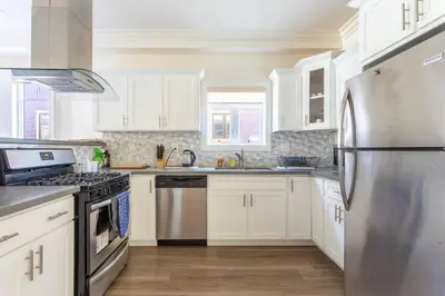 a kitchen with white cabinets and a stainless steel refrigerator at Getaway 4BR Home in the Heart of LA in Los Angeles