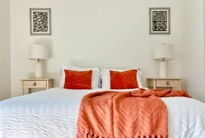 a bedroom with a large white bed with red pillows at West Hollywood Gem 2-Bedroom Apartment in Los Angeles