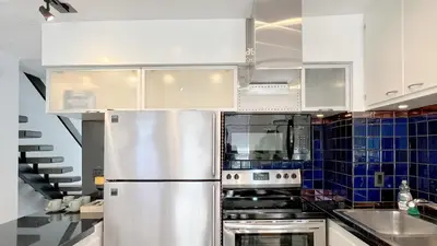 a kitchen with white cabinets and a stainless steel refrigerator at Coastal Retreat Steps from the Santa Monica Beach in Los Angeles
