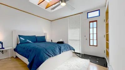 a bedroom with a bed with a blue comforter and a window at Coastal Retreat Steps from the Santa Monica Beach in Los Angeles
