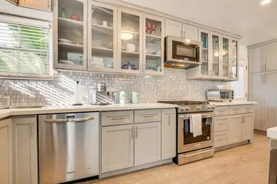 a kitchen with white cabinets and stainless steel appliances at 4 Mi to Beach Chic Los Angles Home with Patio! in Los Angeles