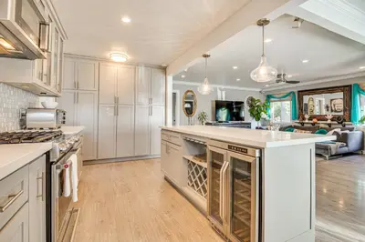 a large kitchen with white cabinets and a large island at 4 Mi to Beach Chic Los Angles Home with Patio! in Los Angeles