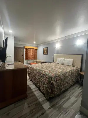 a hotel room with a bed and a flat screen tv at Amber Motel in Inglewood