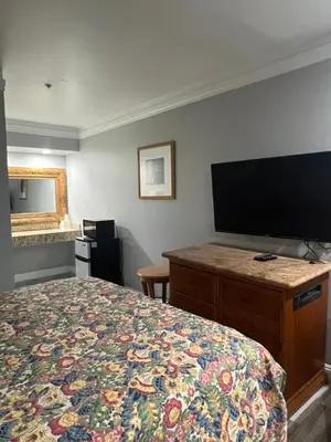 a hotel room with a bed and a flat screen tv at Amber Motel in Inglewood