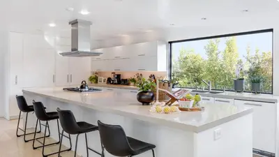 a kitchen with a large white counter with black chairs at Kings Road West Hollywood Luxury Pool Views Firepit Modern Design in Los Angeles