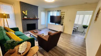 a living room with a green couch and a television at LAX House Near SoFi Stadium, Intuit Dome, YouTube Theater, The Kia Forum, Beaches in Inglewood
