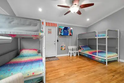 two bunk beds in a room with a ceiling fan at Carnival Dream by OC Adventure Homes in Orange