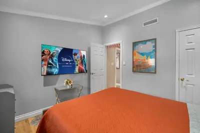 a bedroom with an orange bed and a flat screen tv at Carnival Dream by OC Adventure Homes in Orange