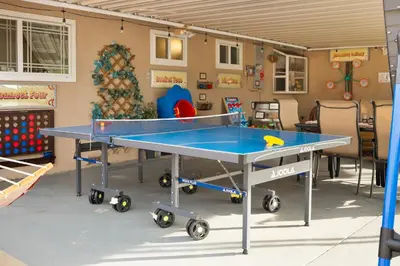a ping pong table in a room with a christmas tree at Carnival Dream by OC Adventure Homes in Orange