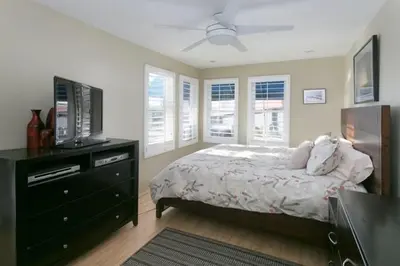a bedroom with a bed and a dresser with a television at 90210 Beach House Lower Unit in Hermosa Beach