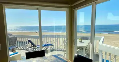 a room with a view of the beach from a balcony at 90210 Beach House Top Unit in Hermosa Beach