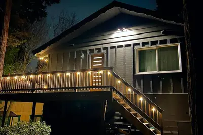 a house with lights on the deck at night at Beautiful Renovated Cozy Forest Home with Hot Tub in Crestline in Crestline