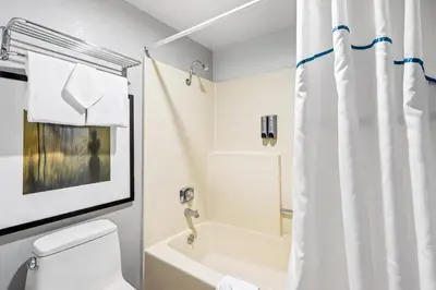a bathroom with a white shower curtain and a toilet at HomeTowne Studios by Red Roof Ridgecrest in Ridgecrest