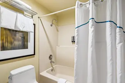 a bathroom with a white shower curtain and a toilet at HomeTowne Studios by Red Roof Ridgecrest in Ridgecrest
