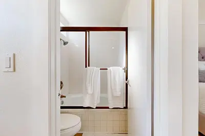a bathroom with a toilet and a shower with white towels at Lake Arrowhead Views! Condo with Shared Pool and Spa in Lake Arrowhead