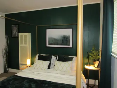 a bedroom with a canopy bed with green walls at Forest Moon Cottage in Big Bear City Airport