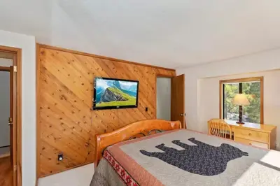 a bedroom with a bed and a wooden wall at The Mountain Treehouse, Jacuzzi Large Backyard! in Big Bear Lake