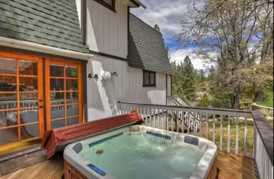 a hot tub on the deck of a house at The Mountain Treehouse, Jacuzzi Large Backyard! in Big Bear Lake