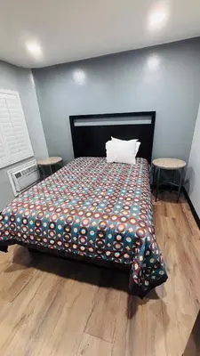 a bedroom with a bed with a pillow and two tables at vogue motel in South Gate
