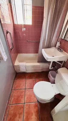 a bathroom with a toilet and a tub and a sink at vogue motel in South Gate