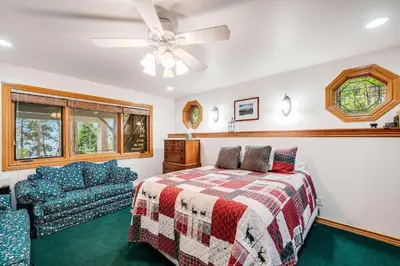 a bedroom with a bed and a couch and a ceiling fan at Navigate Stays Best Dressed Lakefront Home in Lake Arrowhead