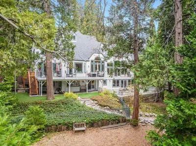 a large white house in the woods with trees at Navigate Stays Best Dressed Lakefront Home in Lake Arrowhead