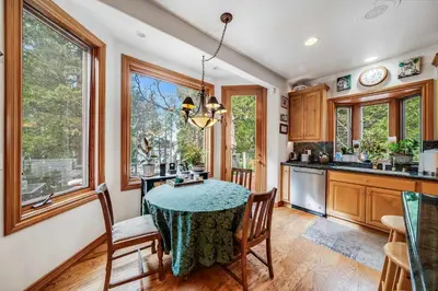 a kitchen with a table and chairs and windows at Navigate Stays Best Dressed Lakefront Home in Lake Arrowhead