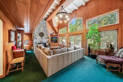 a living room with a large couch and some windows at Navigate Stays Best Dressed Lakefront Home in Lake Arrowhead