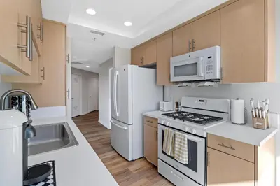 a kitchen with white appliances and wooden cabinets at Coastal Bliss - Luxe 2BR Retreat in MDR - Venice - SM in Los Angeles