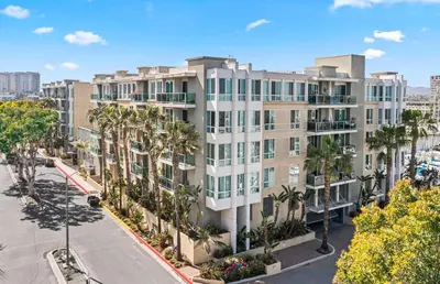 an apartment building with palm trees in front of a street at Coastal Bliss - Luxe 2BR Retreat in MDR - Venice - SM in Los Angeles