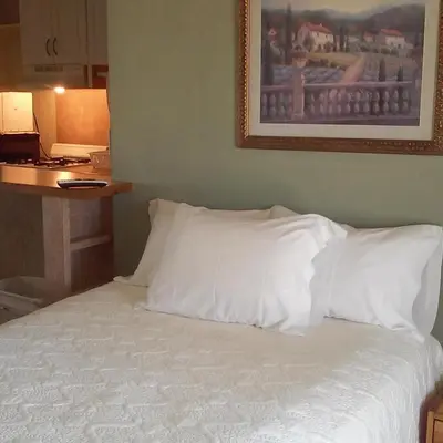 a bed with white pillows and a picture on the wall at Hilltop Tavern and Inn in Apple Valley