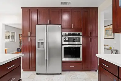 a stainless steel refrigerator in a kitchen with wooden cabinets at Luxury Estate with Sparkling Pool & Elegant Amenities in Glendora