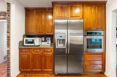 a kitchen with wooden cabinets and stainless steel refrigerator at Adorable 4 bedroom home with Pool & more in Los Angeles