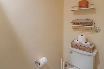 a bathroom with a toilet with two shelves on the wall at Disneyland Retreat Fun Family Unit w Game Room, King Beds & EV Friendly - Sleeps up to 14 in Midway City