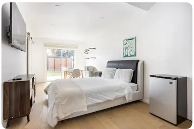 a white bedroom with a bed and a television at Charming one bed one bath privet studio in Tarzana