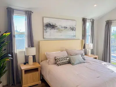 a bedroom with a bed with two lamps and windows at Central North Hollywood Home in Los Angeles