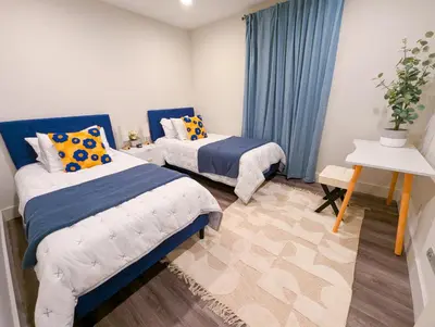 two beds in a room with blue curtains and a table at Central North Hollywood Home in Los Angeles