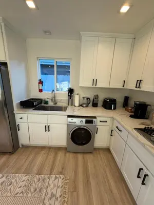 a kitchen with white cabinets and a washing machine at Cute House in West Valley Area Heliport