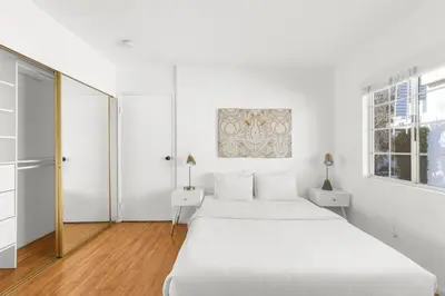 a white bedroom with two beds and a window at Modern Furnished 2 Bedroom in West LA in Los Angeles