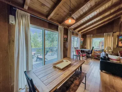 a dining room with a wooden table and a large window at Casita de Sergio - Peek-A-Boo Lake View, Walk to Lake, Fireplace in Big Bear Lake