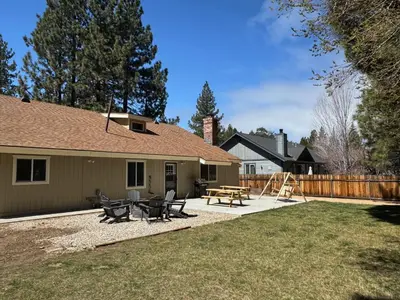 a backyard with a house with a picnic table and chairs at Eagle Point Retreat - Sleeps 13 - 12 Adults Max, Game Room, Foosball, Fireplace, Deck, Barbecue in Big Bear Lake