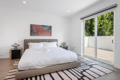 a white bedroom with a bed and a large window at Stunning 3-BR Residence with Free Parking & Patio in Los Angeles