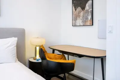 a room with a bed and a desk and a table at Experience Lavish LA Living Sleek 2BR with Parking in Los Angeles