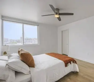 a white bedroom with a bed and a ceiling fan at Modern Marina Escape with Harbor Views in Los Angeles