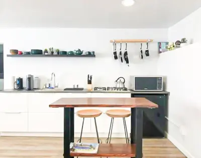 a kitchen with a wooden table and two stools at Cozy LA Studio Steps from SoFi and LAX - SH3 - LAD in Los Angeles