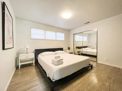 a bedroom with a large bed and a mirror at Bright 2-BR Home Near LAX with Shared Yard - SH2-LAD in Los Angeles