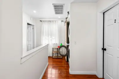 a hallway with white walls and wooden floors and a door at Game Room & In-Unit Laundry - 15 Min to Disney! in Artesia